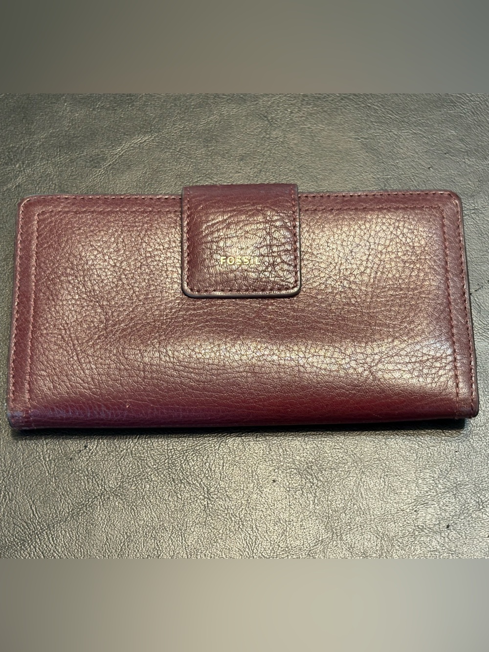 Fossil pebbled leather tab clutch wallet in a deep burgundy or berry color